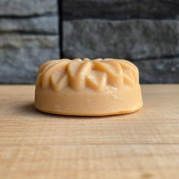 Arctic Breeze round sunflower-moulded salt soap bar on a wood table, real product photo