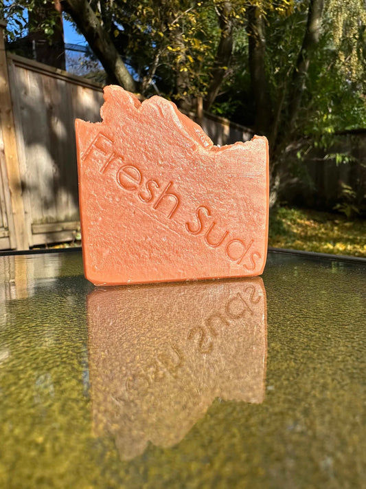 Warm Sauna soap bar, featuring a rich blend of iris, violet, jasmine and citrus, enriched with French Red clay, capturing the essence of a soothing sauna experience in a luxurious cleansing bar.