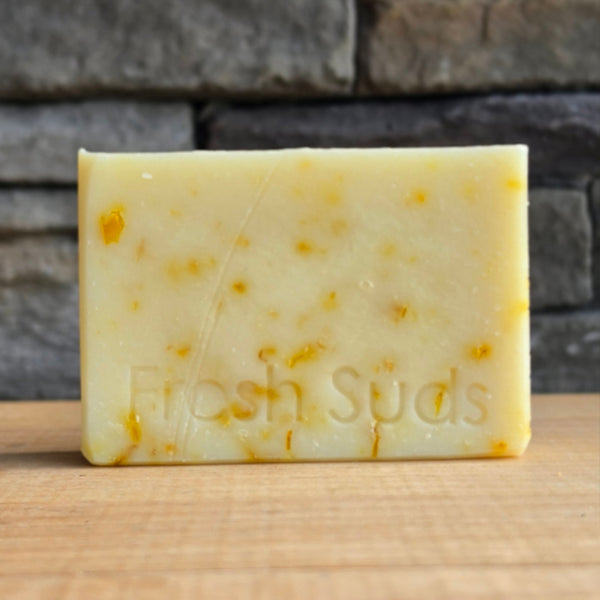 Serenity Calendula soap bar on a wood table, real product photo
