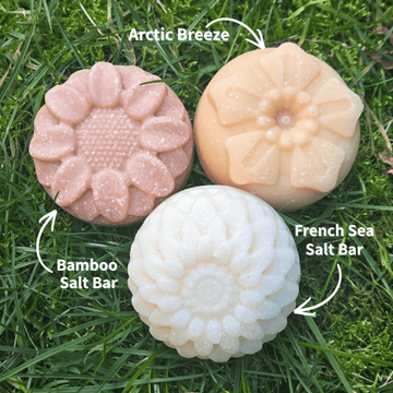 Three flower-shaped Fresh Suds salt soap bars — Arctic Breeze, Bamboo, and French Sea Salt — on a grassy background