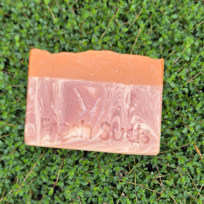 Mango Surprise soap bar on a wood surface with fresh thyme, real product photo