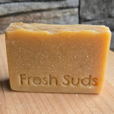 Restore Dandelion soap bar against a wood wall, real product photo