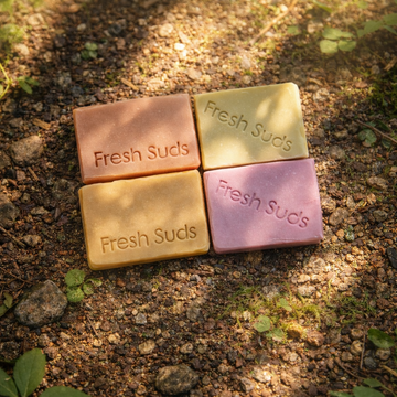 Self Care Soap Bundle - Four bars of 'Fresh Suds' soap in different colours on a textured forest ground background. - Fresh Suds Soapery