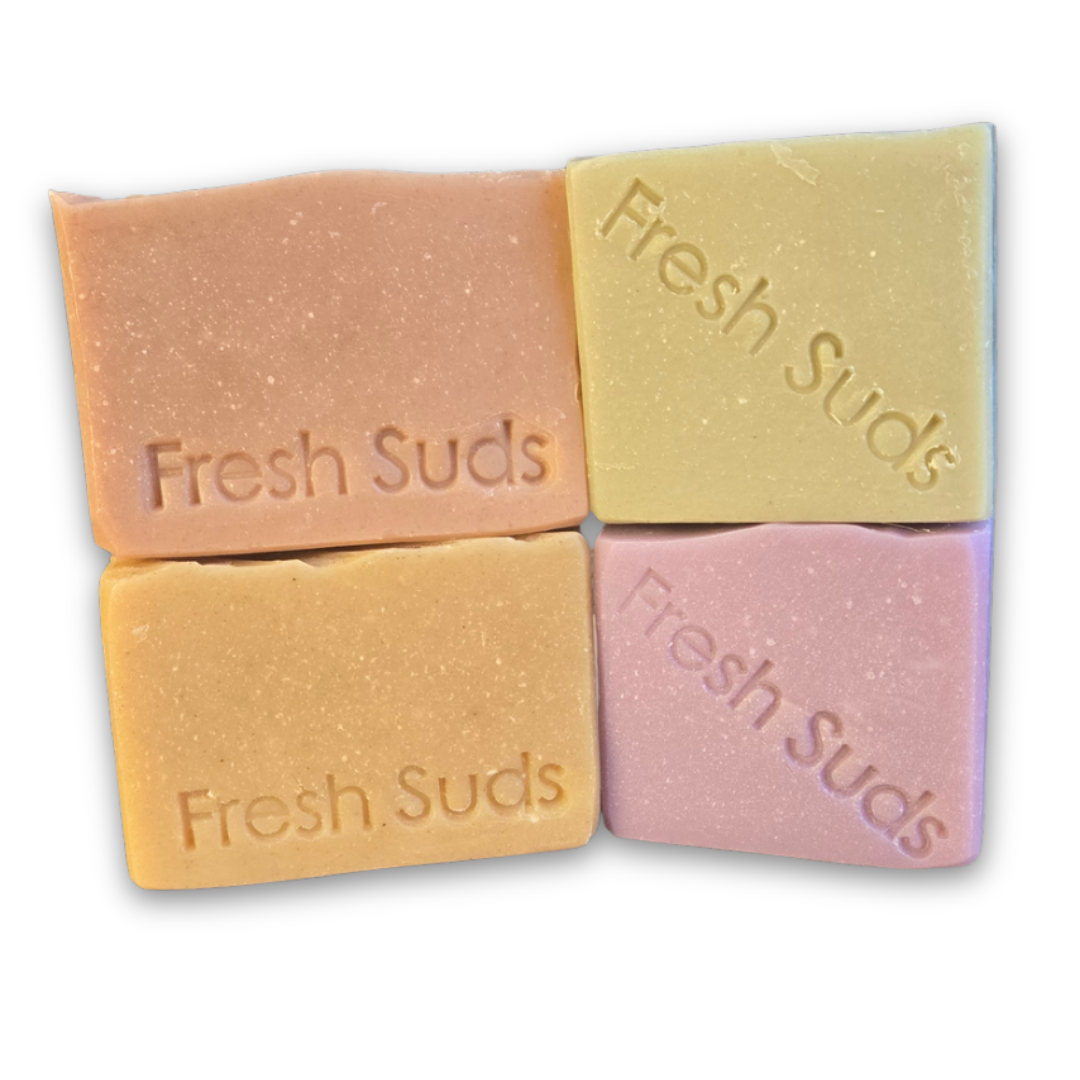Self Care Soap Bundle - Four bars of 'Fresh Suds' soap in different colours on a textured forest ground background. - Fresh Suds Soapery