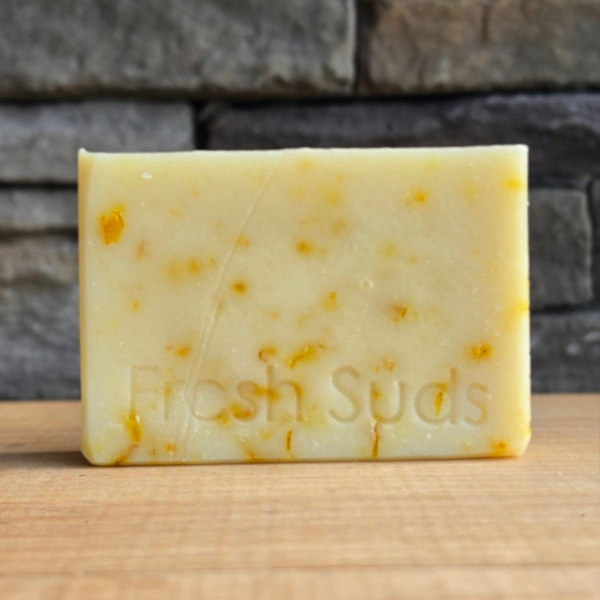 Serenity Calendula soap bar on a wood table, real product photo