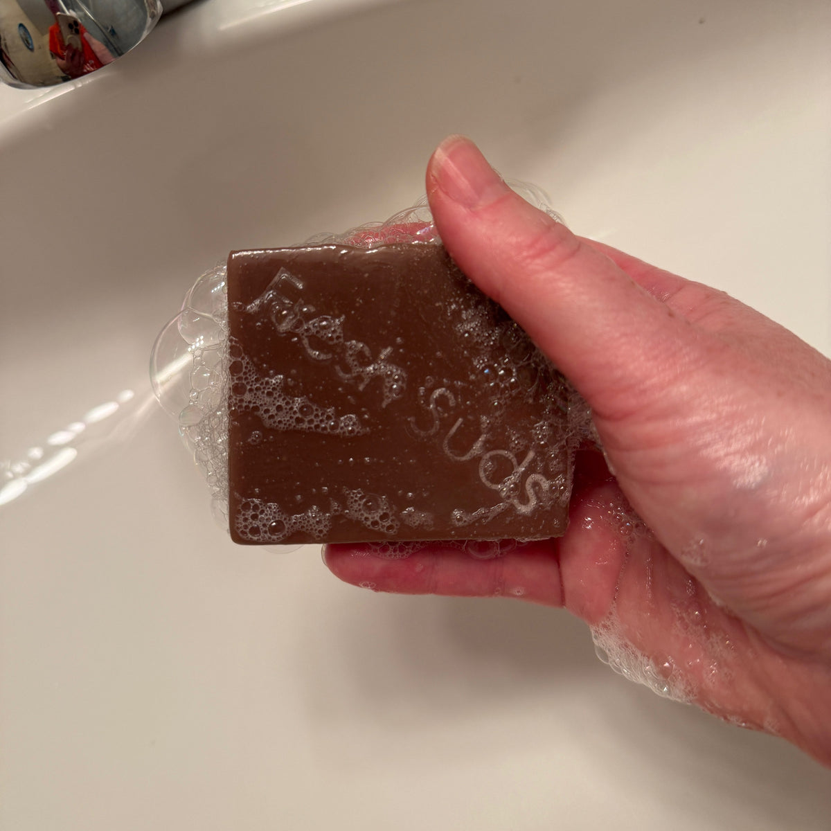 Purple Clay Detox bar suds in hand, from the True North bundle, real product photo