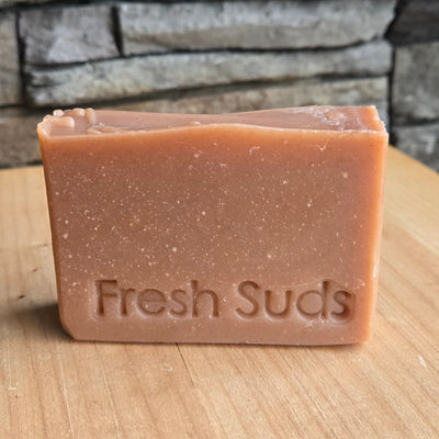Youthful Glow Rosehip soap bar against a wood wall, real product photo