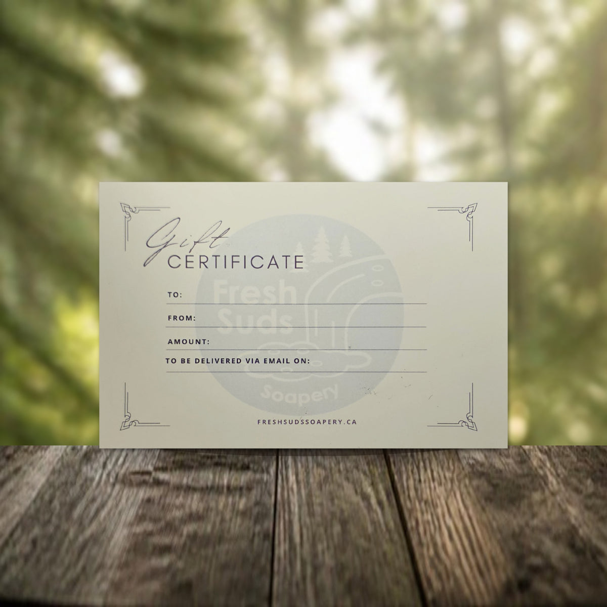 Fresh Suds Soapery gift certificate on a wooden table with a forest background